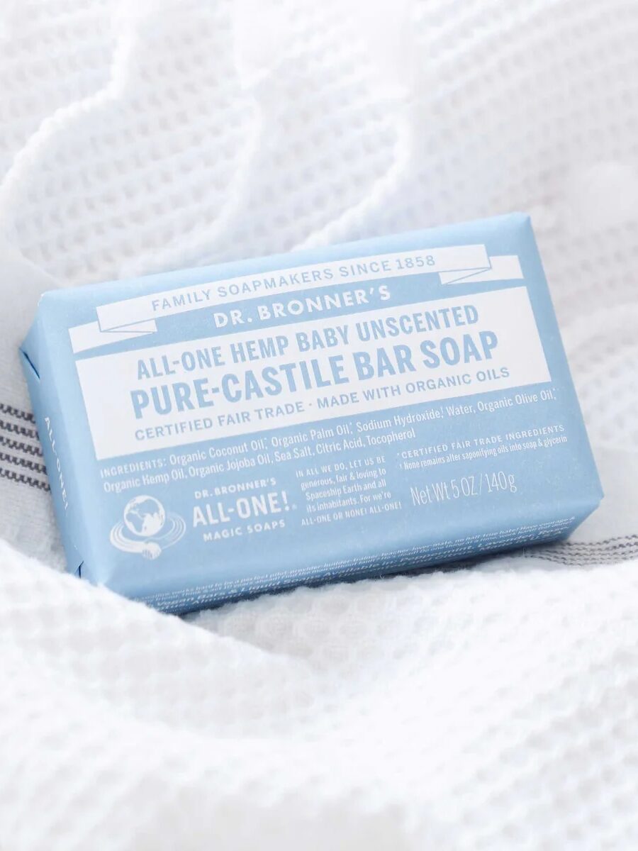 A bar of Dr. Bronner's All-One Hemp Baby Unscented Pure-Castile Bar Soap rests on a white textured cloth.