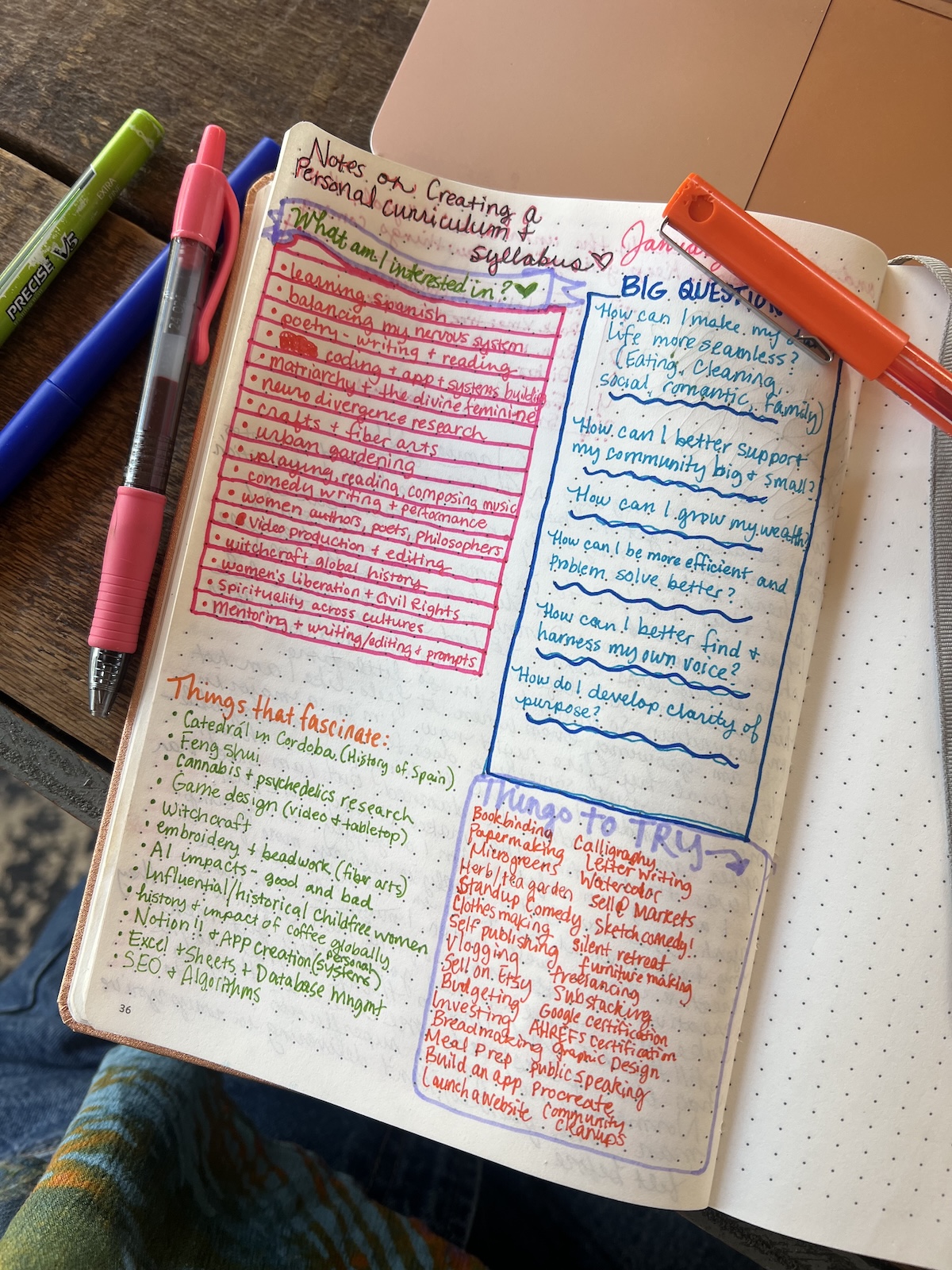 Open notebook page with color-coded handwritten notes, pens, and a highlighter nearby. Notes include lists, questions, and goals for creating a personal curriculum or syllabus.