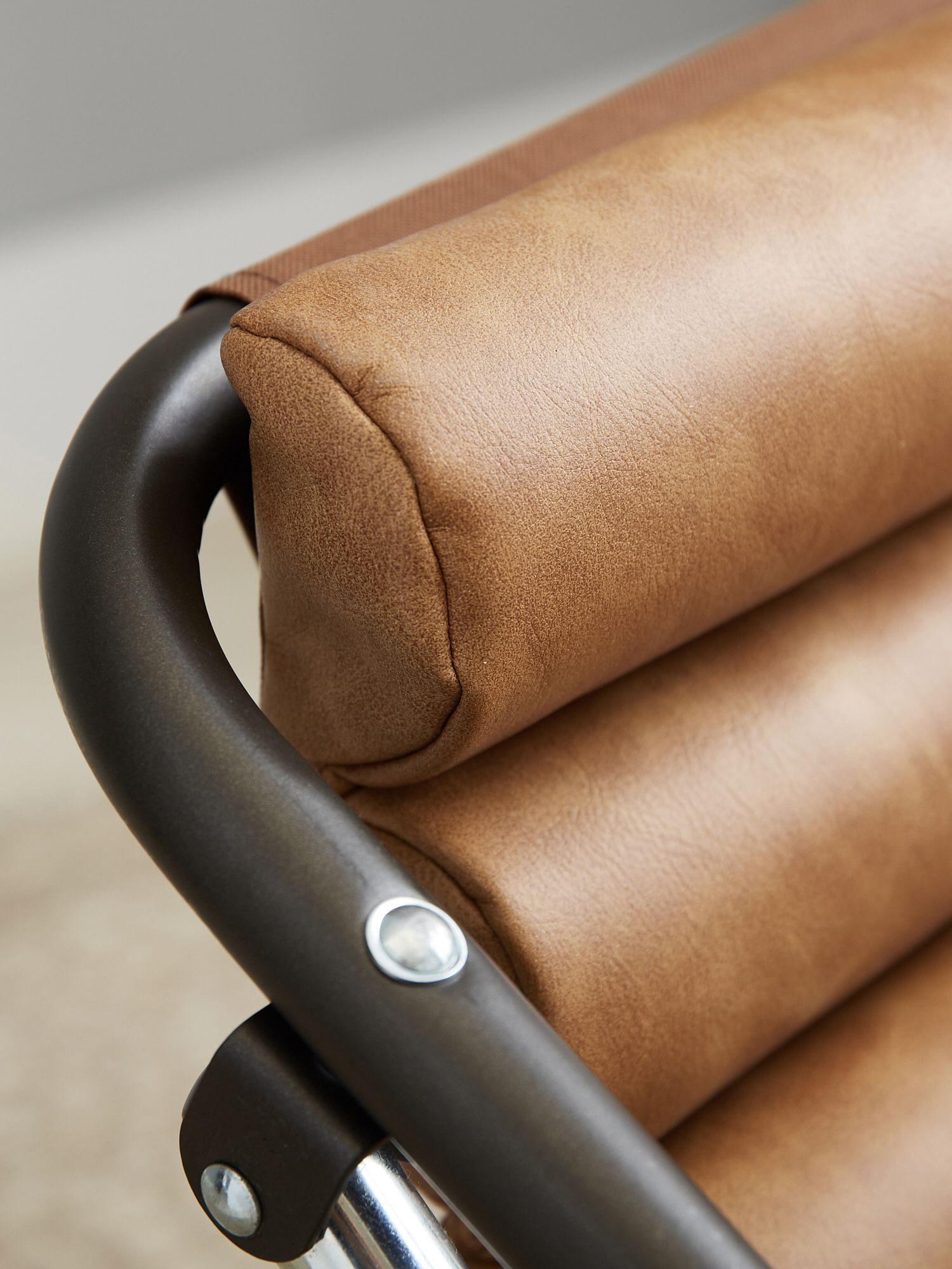 Close-up of a modern chair with brown cushioned backrest and a black metal frame, highlighting the texture and material of the upholstery.