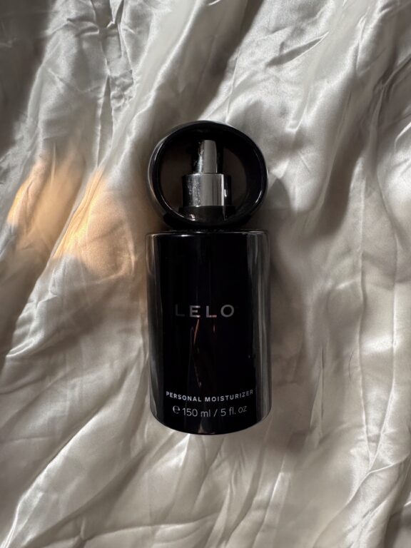 A black bottle labeled "LELO Personal Moisturizer," 150 ml (5 fl. oz), with a pump top, placed on a silky, light-colored fabric.