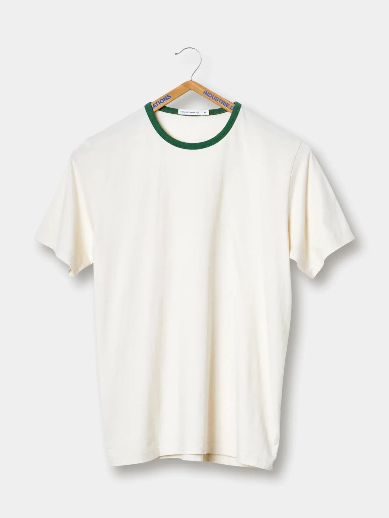 White t-shirt with a green neckline on a wooden hanger against a plain background.