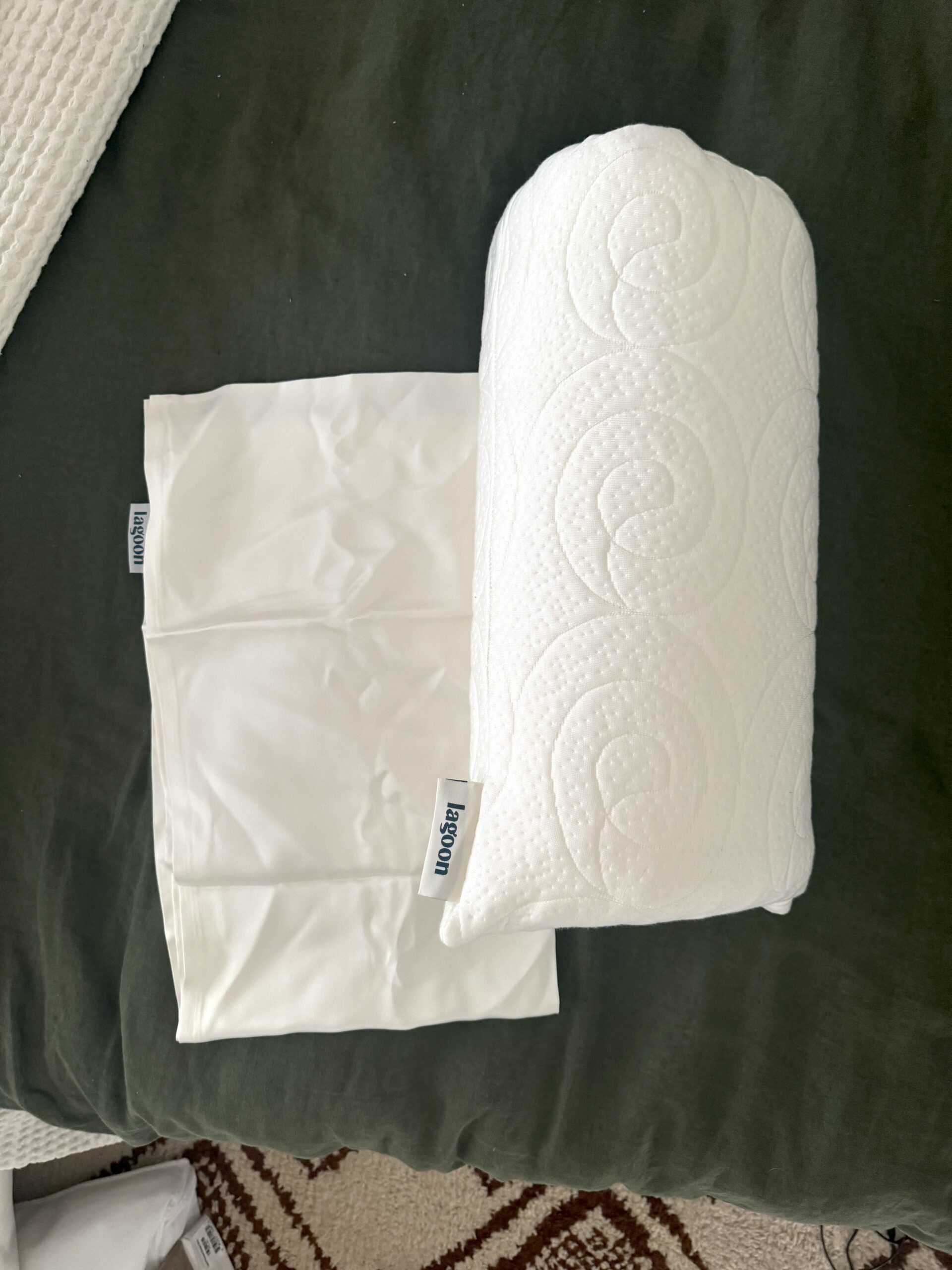 White ergonomically shaped pillow and cover with a textured spiral pattern placed on a dark green surface.