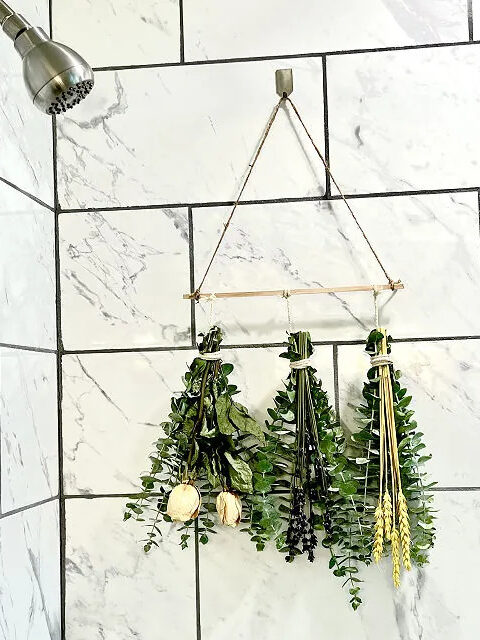 A Eucalyptus Trip handing in a shower off a wooden rod. By Uncommon Goods.