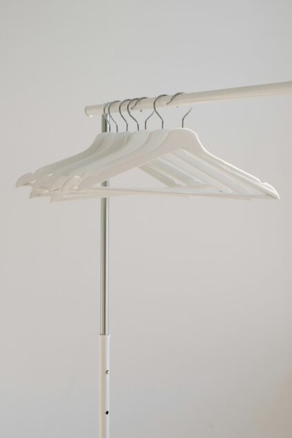 White hangers on a clothing rack against a plain background.