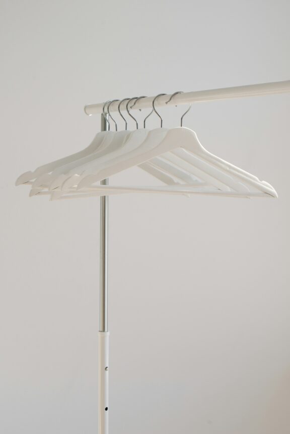 White hangers on a clothing rack against a plain background.
