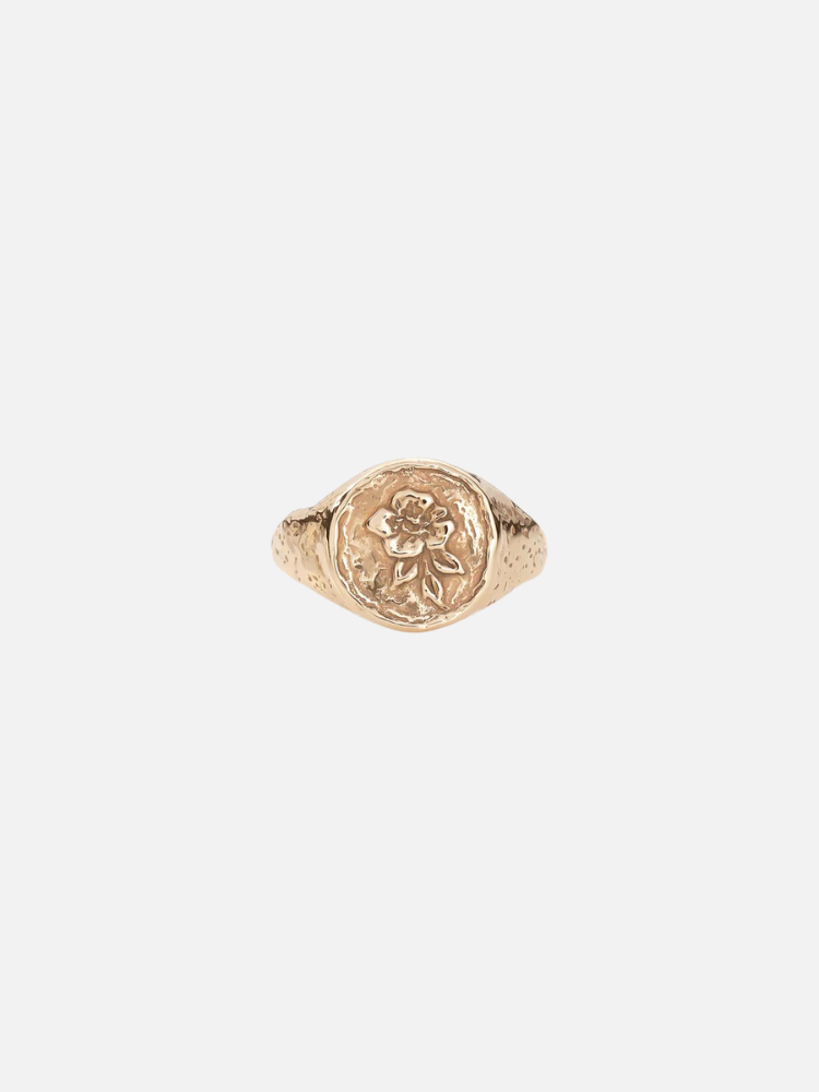 Gold ring featuring an embossed design of a flower on its round face.