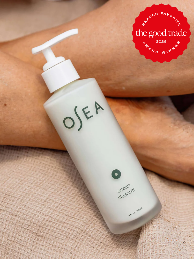 A bottle of OSEA Ocean Cleanser with a pump top rests on a person's legs, with a "The Good Trade 2026 Reader Favorite Award Winner" badge in the upper right corner.