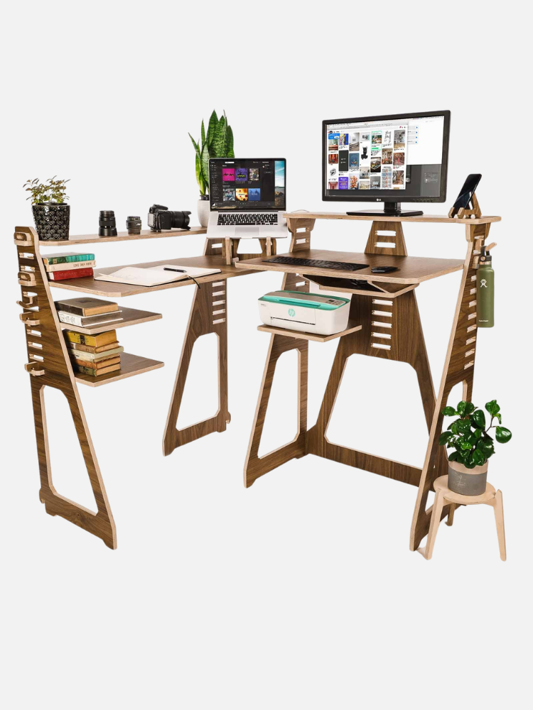 A modern wooden L-shaped desk with multiple shelves, a laptop, monitor, plants, books, and office supplies arranged neatly on and around it.