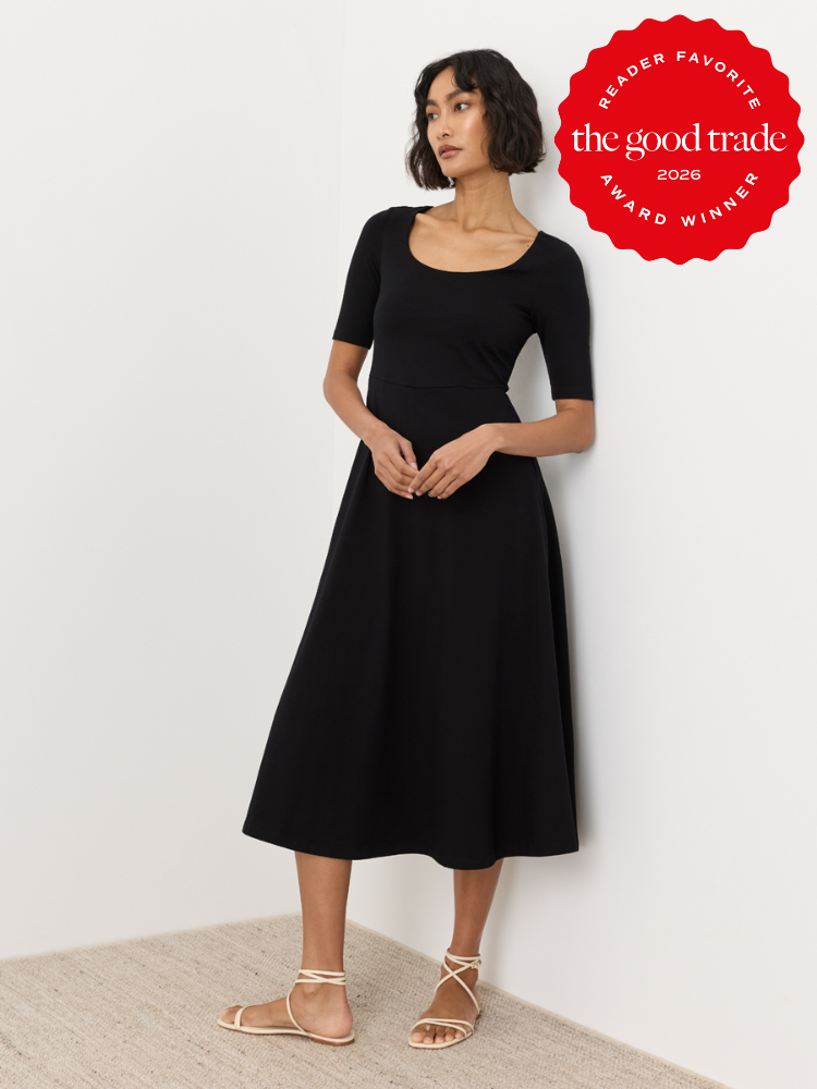 Woman stands against a white wall wearing a black midi dress and beige lace-up sandals. A red "The Good Trade 2026 Reader Favorite Award Winner" badge appears in the top right corner.